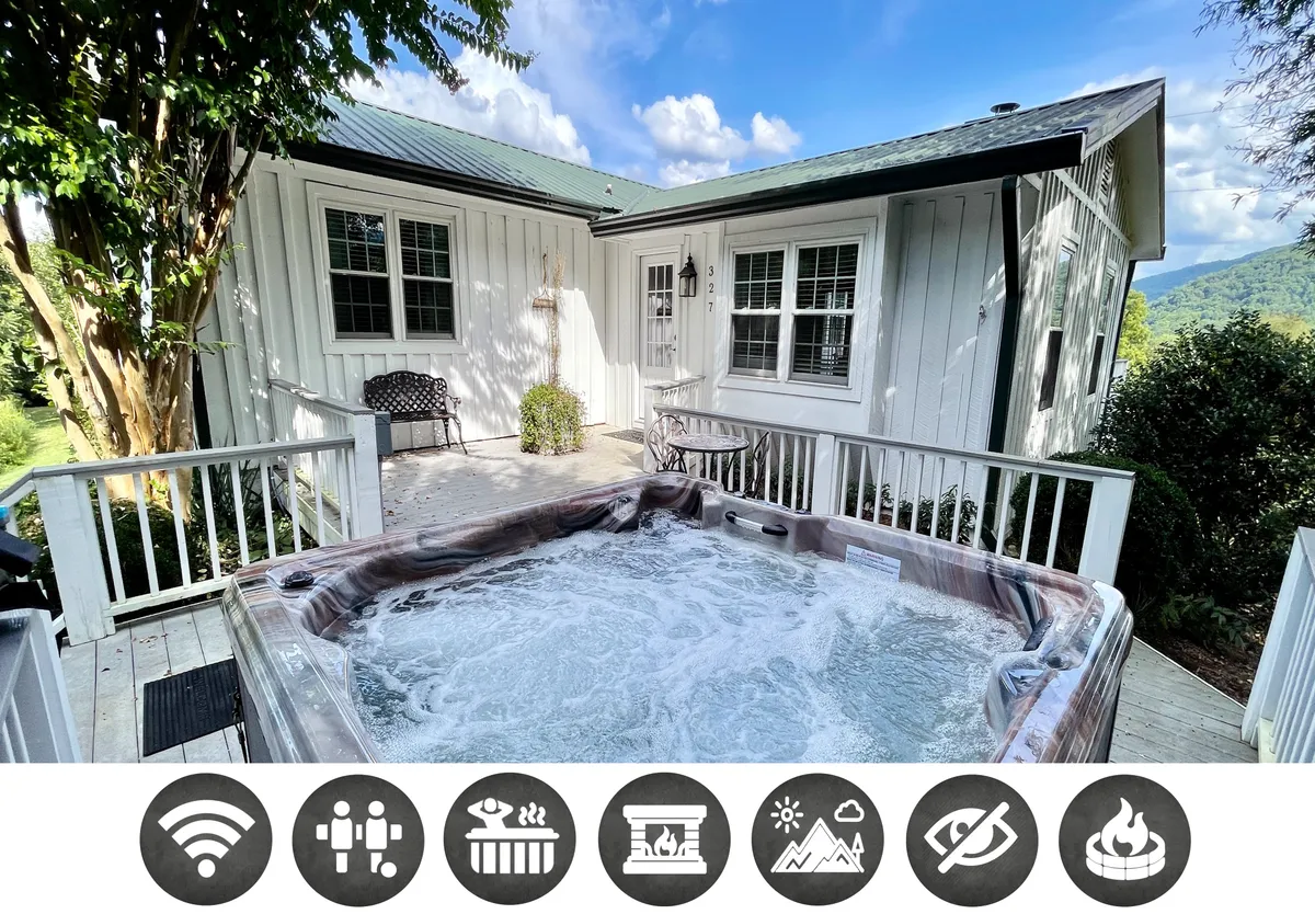 The image showcases the exterior of a cozy single-family house nestled in lush greenery, with a bubbling hot tub on the deck overlooking serene mountain views. The inviting outdoor seating area sets the scene for gatherings, relaxation, and enjoying beautiful sunsets or stargazing at night.
