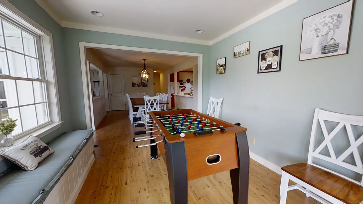 A lively game room featuring a foosball table as the main centerpiece, complemented by cozy built-in window seating and decorative wall art. The space exudes a playful and inviting atmosphere, perfect for social gatherings and family fun.