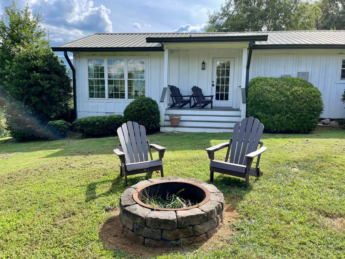 This image features two Adirondack chairs centered around a fire pit on the front porch, evoking a sense of outdoor relaxation and family-friendly fun. The seating arrangement encourages gatherings for conversation or roasting marshmallows, while the fire pit hints at cozy evenings after a day filled with adventure.