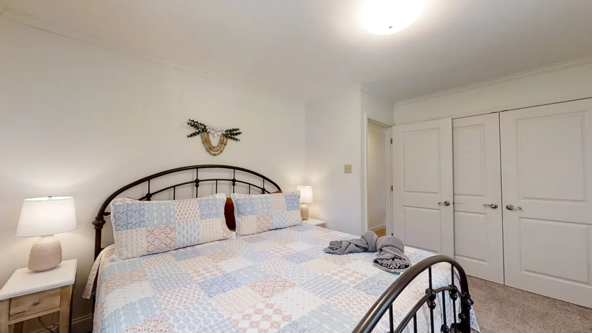 A tranquil bedroom with a bed dressed in a patchwork quilt, a nightstand with a lamp for bedtime reading, and decorative wall art. Soft lighting and thoughtful decor enhance the sense of comfort and privacy.